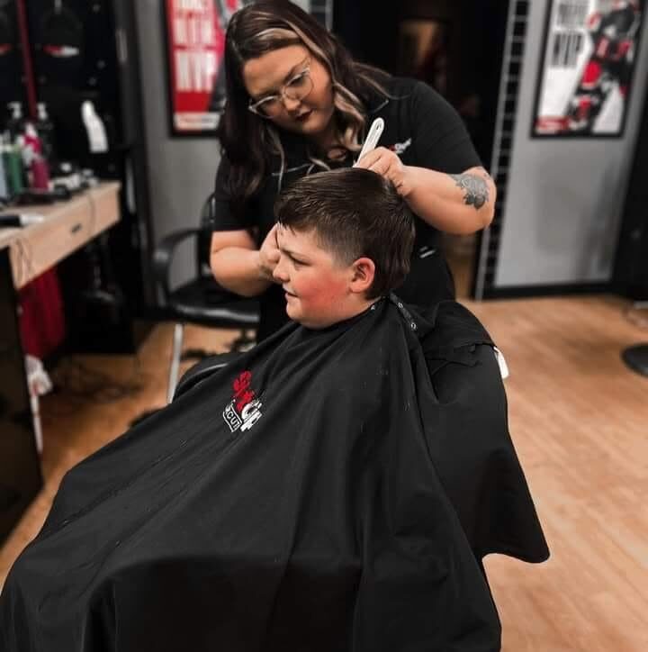 Macy cutting a young client's hair in the barber studio